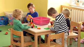 Kinder spielen mit Bausteinen auf einem kleinen Tisch