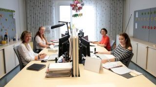 Arbeitssituation: Vier Personen sitzen an Schreibtischen in einem Bro