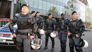 Eine Polizistin und fnf Polizisten in Schutzkleidung vor einem Stadion